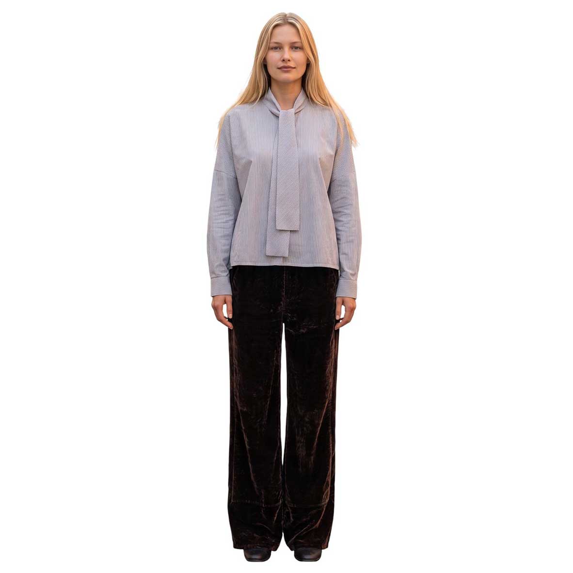 Model wearing La Sartoria Pettegole brown pinstripe bow collar blouse with long sleeves, styled with dark brown velvet wide-leg pants.