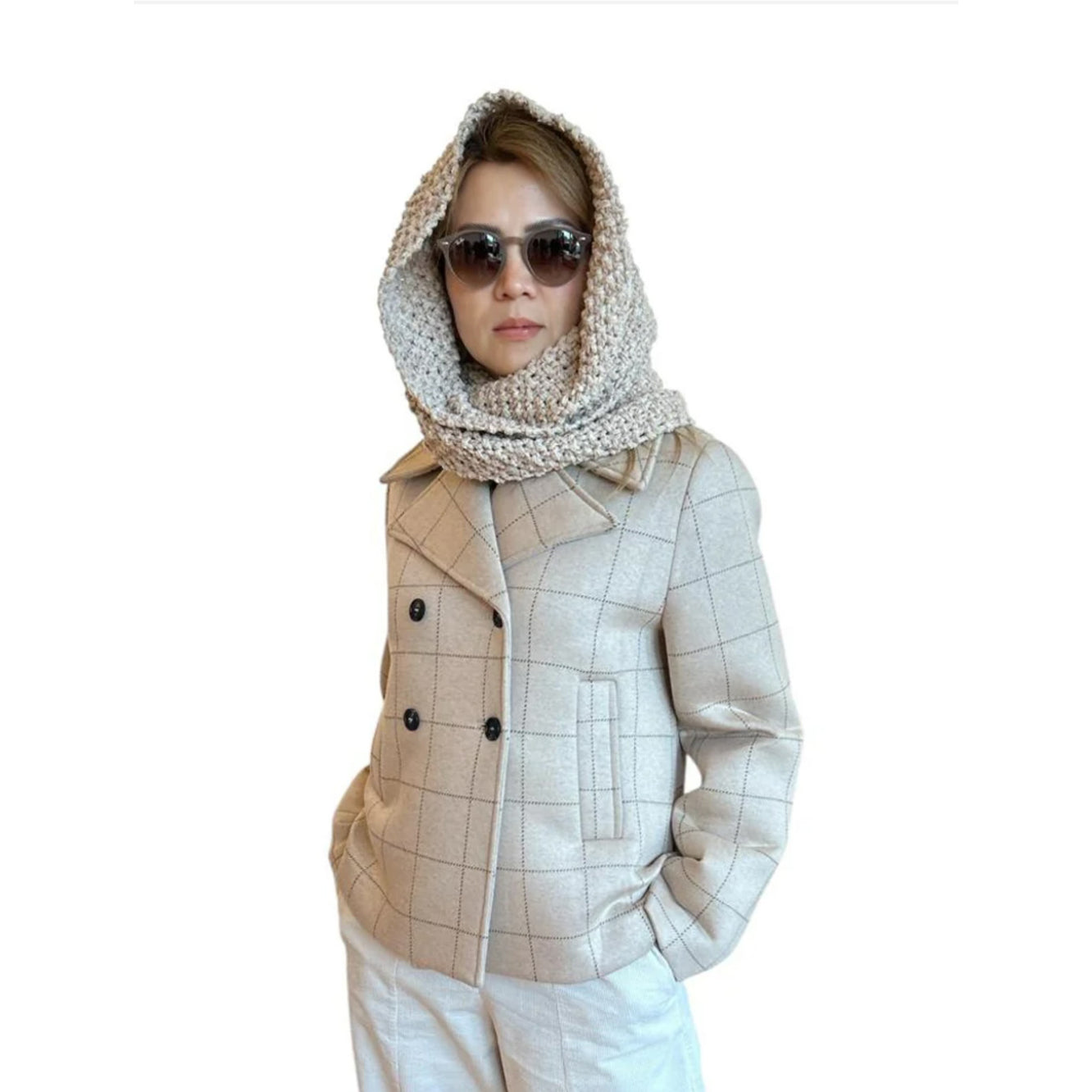 Person wearing a beige checkered jacket, white pants, and sunglasses on a white background