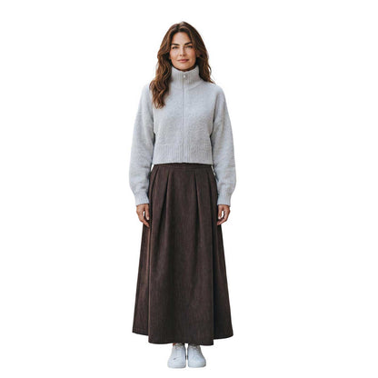 Woman wearing a high neck zipped mohair sweater in oatmeal by Sand, sold at Aqualta, styled with a long dark skirt and white sneakers.