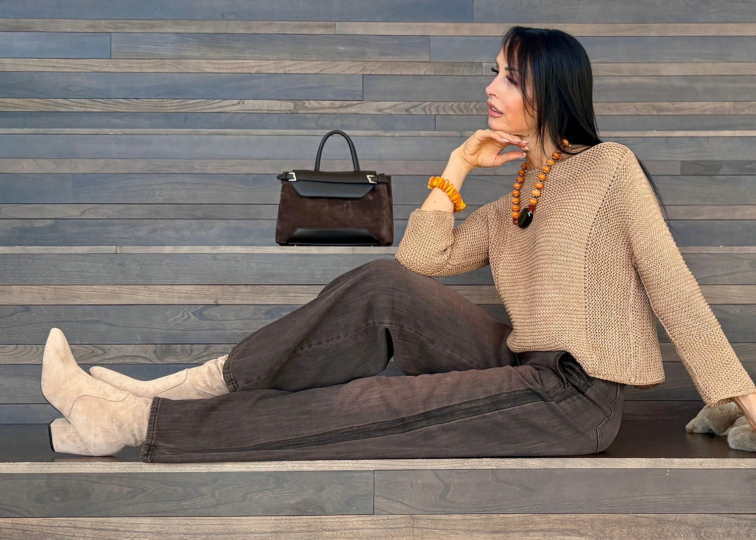 Woman sitting on steps with a handbag and coat beside her