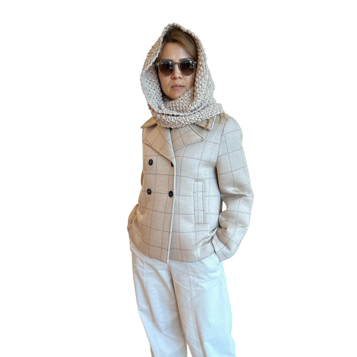 Person wearing a beige checkered jacket, white pants, and sunglasses on a white background
