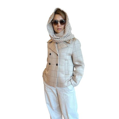Person wearing a beige checkered jacket, white pants, and sunglasses on a white background