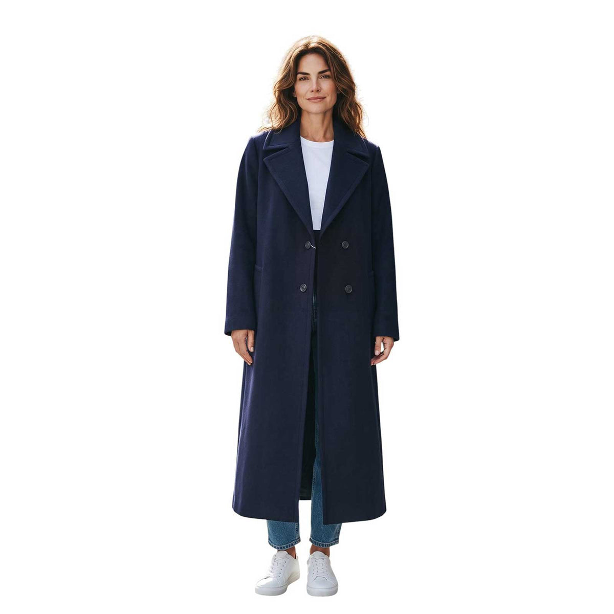 Woman wearing a long navy cashmere blend coat by Sand, sold at Aqualta, with a white top, blue jeans, and white sneakers.
