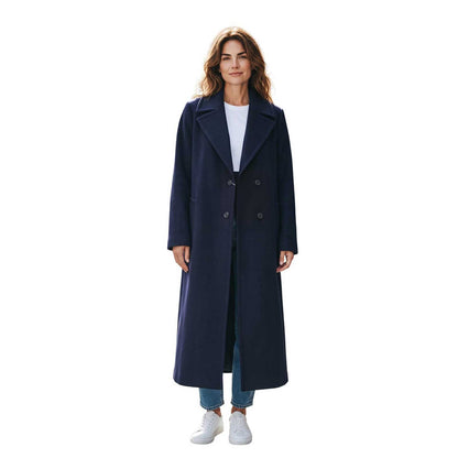 Woman wearing a long navy cashmere blend coat by Sand, sold at Aqualta, with a white top, blue jeans, and white sneakers.